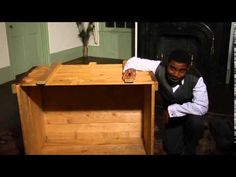 a man kneeling down next to a wooden chest