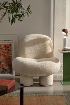 a white chair sitting on top of a floor next to a plant in a living room