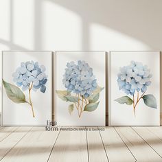 three blue hydrangeas are displayed on the wall in an empty room with wood flooring