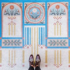 a person standing in front of a tiled wall with flowers and circles on the side