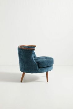 a blue chair sitting on top of a white floor next to a wooden legrest