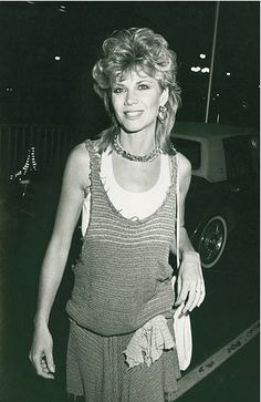 an old photo of a woman walking down the street at night with her hand in her pocket