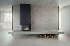 a fireplace in the middle of a room with white walls and flooring on it