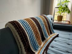 a blue couch with a crocheted blanket on it