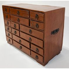 an old wooden dresser with many drawers and knobs on the front, sitting against a white background