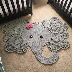 a crocheted elephant rug with a pink bow on it's head in a nursery room