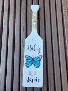 a bottle opener with a blue butterfly on it sitting on a wooden bench that says, big valley little jamie