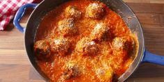 a blue pan filled with meatballs and sauce on top of a wooden table next to a red checkered napkin