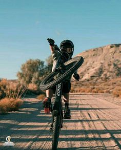 a person riding a bike on a dirt road with mountains in the backgroud