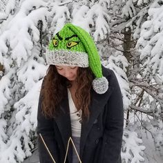 a woman wearing a green hat standing in front of snow covered trees