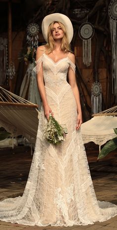 a woman in a white dress and hat standing next to a hammock with flowers