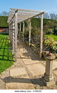 an outdoor garden with stone walkway and pergolated area - stock image