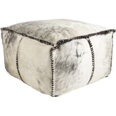 a white and black cowhide ottoman with chains on the bottom, in front of a white background