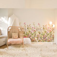 a baby's room with flowers on the wall and a crib next to it