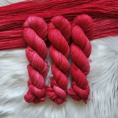 three skeins of red yarn are laid out on a white furnishing