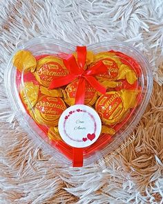 a heart shaped box filled with chocolates on top of a white furnishing