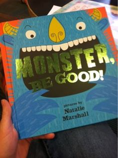 a person holding up a book that says monster be good