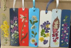 four tags with flowers painted on them hanging from strings