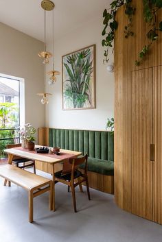 a dining room table with two benches next to it and plants hanging on the wall