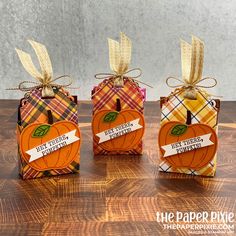 three small pumpkins with tags tied to them on top of a wooden table next to each other