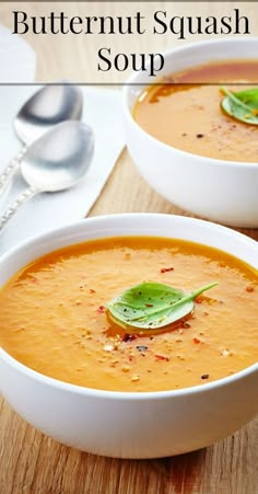 two white bowls filled with soup on top of a wooden table next to silverware