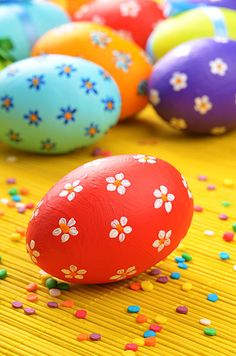 colorfully decorated easter eggs sit on a yellow surface with confetti scattered around them