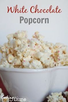 white chocolate popcorn in a bowl with sprinkles on the side and text overlay that reads, white chocolate popcorn