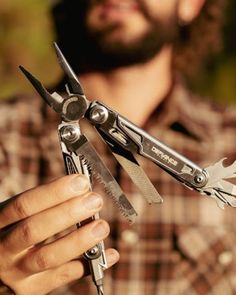 a man holding several pairs of scissors in one hand and another with two blades on the other