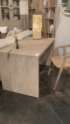 a wooden table and chair in a room with other items on the shelves behind it