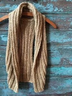 a brown knitted scarf hanging on a wooden hanger against a blue painted wall