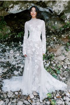 a woman in a wedding dress standing on rocks