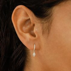 a woman's ear is shown with a pair of earrings in the shape of a flower