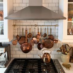 pots and pans are hanging on the wall above the stove