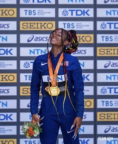 a woman standing on top of a winners podium with her medal in front of her face