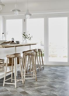 a kitchen with several stools in front of an island and large glass doors to the outside