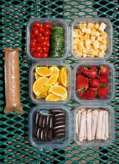 four plastic containers filled with food on top of a green mesh tablecloth covered surface