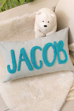 a teddy bear sitting next to a pillow with the word jacob on it