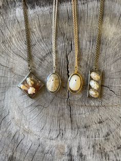 three necklaces with shells in them sitting on a piece of wood