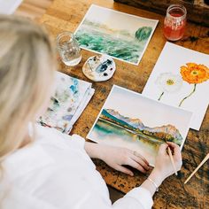 a woman is working on some art work with watercolors and paintbrushes