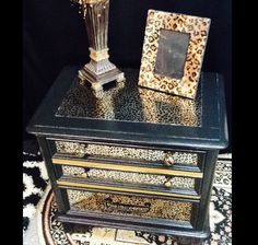 an animal print table with a lamp on top and a photo frame sitting on it