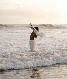 a woman is standing in the water at the beach