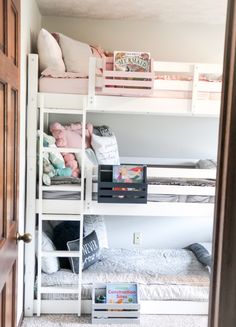 a bunk bed room with two sets of bunk beds and books on the bottom shelf