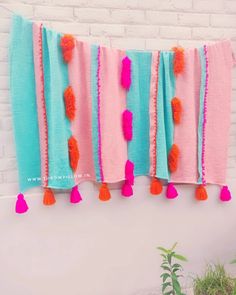 a colorful wall hanging with tassels and pom - poms on it