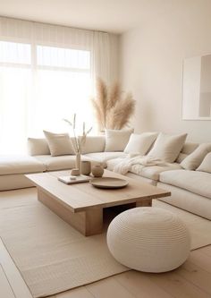 a living room with white couches and pillows on top of the floor next to a large window