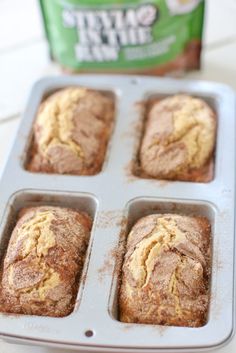 four muffins in a pan next to a carton of tea