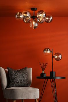 a chair and table in a room with an orange wall, lamp and floor lamp