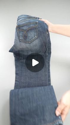 someone is holding up an old pair of jeans with the bottom pocket open and there is a video showing how to fold them