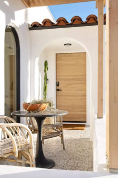 a patio with chairs and a table in front of a door that has a cactus on it