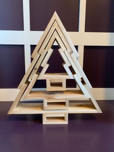 a wooden pyramid made out of pieces of wood on top of a purple countertop