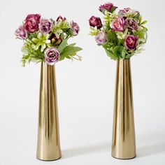 two gold vases with flowers in them on a white background, side by side